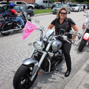 Woman in Black on Motorcycle with Breast Cancer Flag